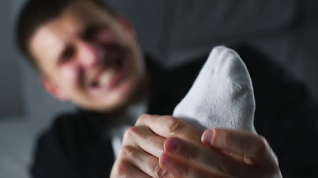 A young man has a foot injury.
A man hit his foot on a sharp object and is screaming in pain.
The man is holding his injured heel with his hand.