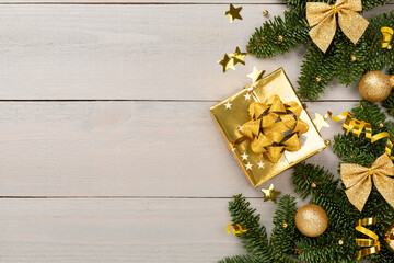 Festive Christmas tree branches with gift box on wooden background, top view