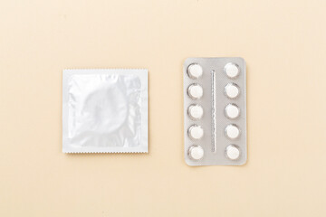 Contraceptive pills and condoms on color background, top view. birth control methods