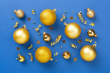 Golden Christmas balls with decor on color background, top view