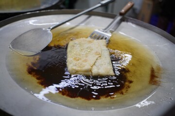 Close-up of a crispy martabak being fried on a large flat pan, a popular snack in Southeast Asia.