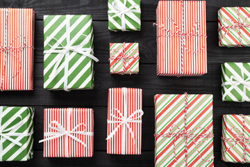 Many striped Christmas gift boxes on wooden background, top view