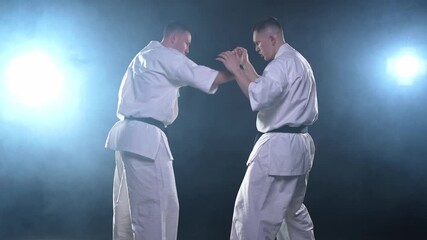 Martial arts masters on dark background. Strong man fighters in white kimono for karate martial arts fighting training in black gym. Karate fighters training punches kicks practicing fight sparring - Powered by Adobe
