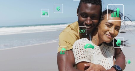 Smiling couple hugging on sandy beach, displaying digital sustainability icons and smartwatch