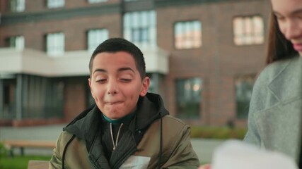 Boy laughs in surprise as aunt makes mistake during playful moment, both smiling warmly outdoors near building background, capturing joy, family bonding, and candid reaction of shared happiness - Powered by Adobe
