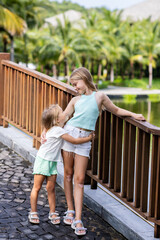 Two adorable caucasian little girls smiling outdoor at hot summer day. Sisters posing in tropical...