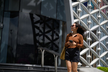 Woman walking urban city looking up carrying shopping bag