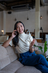 Fototapeta premium Asian woman smiling talking on phone in cafe