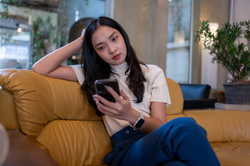 Young woman feeling anxious scrolling smartphone on couch
