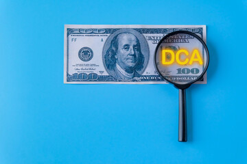 DCA text on magnifying over dollar bank note.
