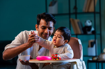 Indian Father and infant boy share bonding moment during mealtime on carpeted floor in home