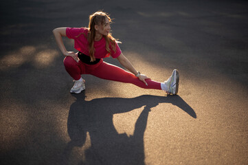 Woman Stretching in Red Sportswear on Asphalt Road