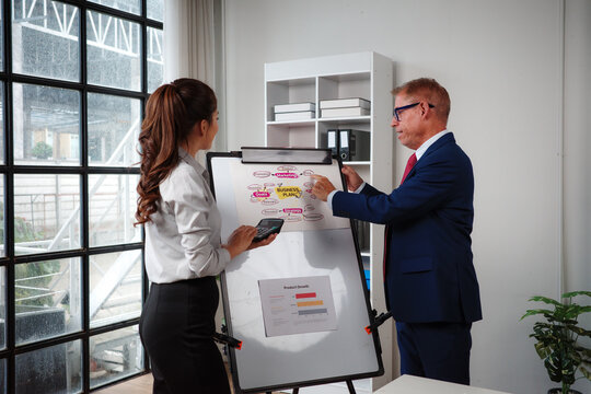 Business colleagues discussing strategy and business plan on whiteboard - Powered by Adobe