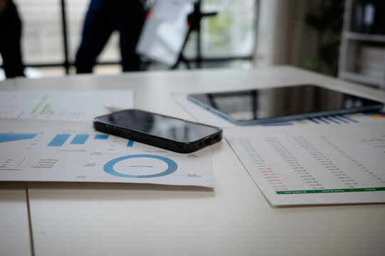 Office desk with documents, charts, smartphone, and tablet