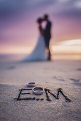 Vertical Close-Up Romantic Wedding Portrait with “E & M” Initials Drawn in Wet Sand – ideal for engagement keepsakes