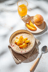 Oatmeal with peaches and nuts  in a bowl on a marble background with honey