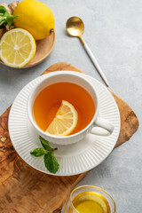 Hot tea with lemon, ginger, honey, and mint in a cup on a wooden board