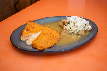 Delicioso platillo de milanesa de pollo rellena acompañada de chilaquiles verdes