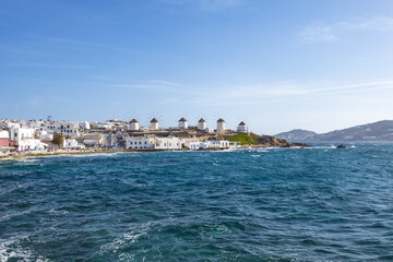 Fototapeta premium scenic view of famous windmills in Chora, Mykonos, Greece. Greek landmark. view of Mykonos Island from the water. deep blue