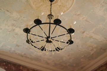 elegant vintage chandelier with pearls hanging from ornate ceiling, adding classic charm to a distressed, textured backdrop. perfect blend of traditional luxury and rustic style.