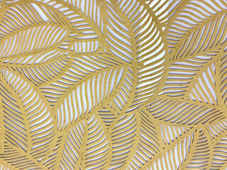 Close up of geometrical leaves shape pattern cutouts in metallic gold paint finish. 3D cutout laser cut foliage leaf shapes suitable for screens or divider. Seamless background texture.
