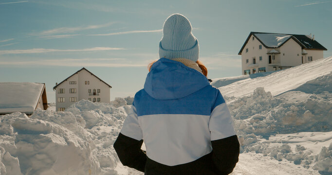 Caucasian woman walking on snow towards winter ski logde. Tourist female coming back to the chalet after morning walk.