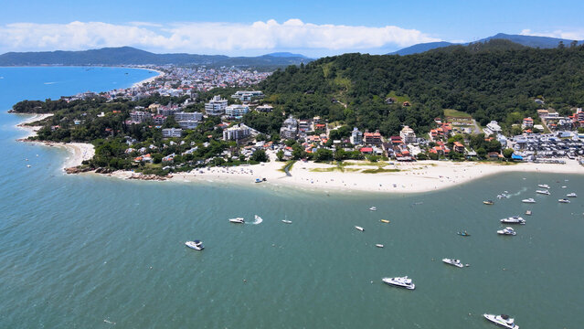 Aerial view of Jurere International, Traditional and Canajure beach in Florianopolis Santa Catarina with boats, yachts and sailboats in the turquoise blue sea with marina and pier.