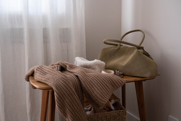 stylish autumn outfit with knited sweater and woman bag on wooden bench, warm fall attire styled for urban city strolls