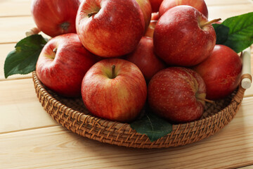 Fresh apples and green leaves on wooden table, closeup