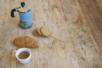 italian moka pot coffee and croissant on rustic wooden table