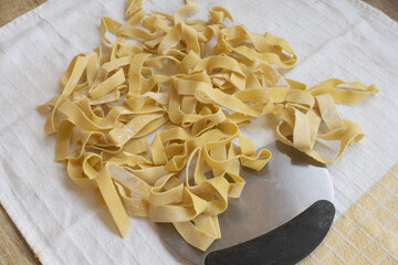 fresh homemade fettuccine pasta on a white cloth with metal cutter