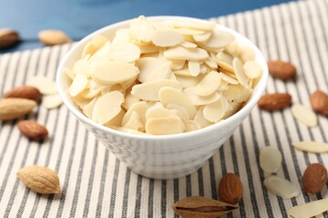 Fresh almond flakes and whole nuts on table, closeup