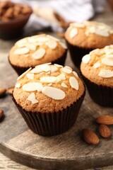 Tasty muffins with almond flakes and nuts on wooden table, closeup