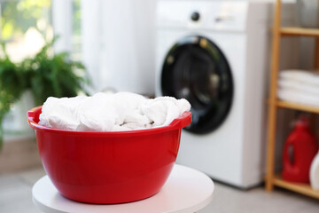 Plastic basin with laundry on white table in bathroom, closeup. Space for text