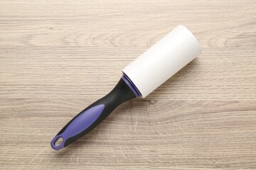 Sticky lint roller on wooden table, top view