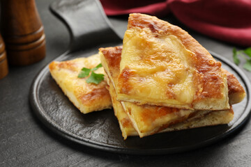 Pieces of delicious Megrelian khachapuri on black table, closeup