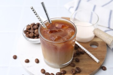 Tasty iced coffee with milk and beans on white table, closeup