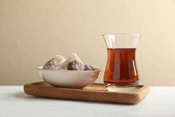 Traditional Turkish tea in glass and sweets on white wooden table, closeup