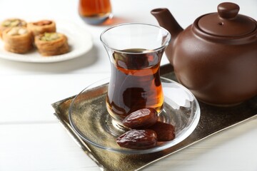 Traditional Turkish tea, dates and sweets on white wooden table, closeup