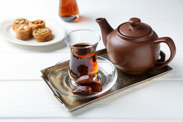Traditional Turkish tea, dates and sweets on white wooden table, closeup