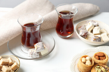 Traditional Turkish tea, brown sugar and sweets on white table, closeup