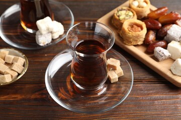 Traditional Turkish tea, brown sugar and sweets on wooden table, closeup