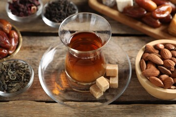 Traditional Turkish tea, dry leaves, sugar and sweets on wooden table, closeup