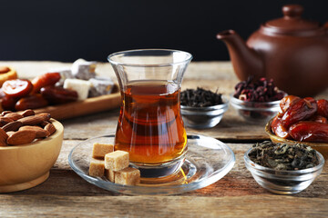 Traditional Turkish tea, dry leaves, sugar and sweets on wooden table, closeup