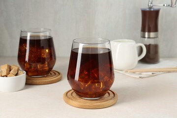 Tasty iced coffee and sugar on white table