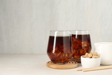 Tasty iced coffee and sugar on white table. Space for text