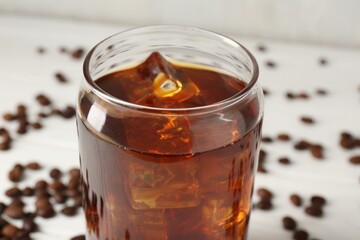 Tasty iced coffee and beans on white table, closeup