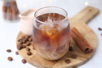 Tasty iced coffee in glass and beans on white table, closeup