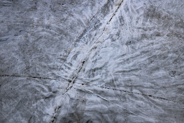 Urban concrete surface with natural cracks and textured gray patterns formed by wear and construction marks