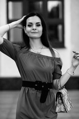 Naklejka premium Elegant woman in off-shoulder dress poses confidently against a textured wall, showcasing her fashion sense and style in a chic urban environment with a sophisticated vibe